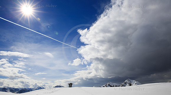 Sonne, Flugzeug, Gewitterwolken, Berge und das Gemeindewappen